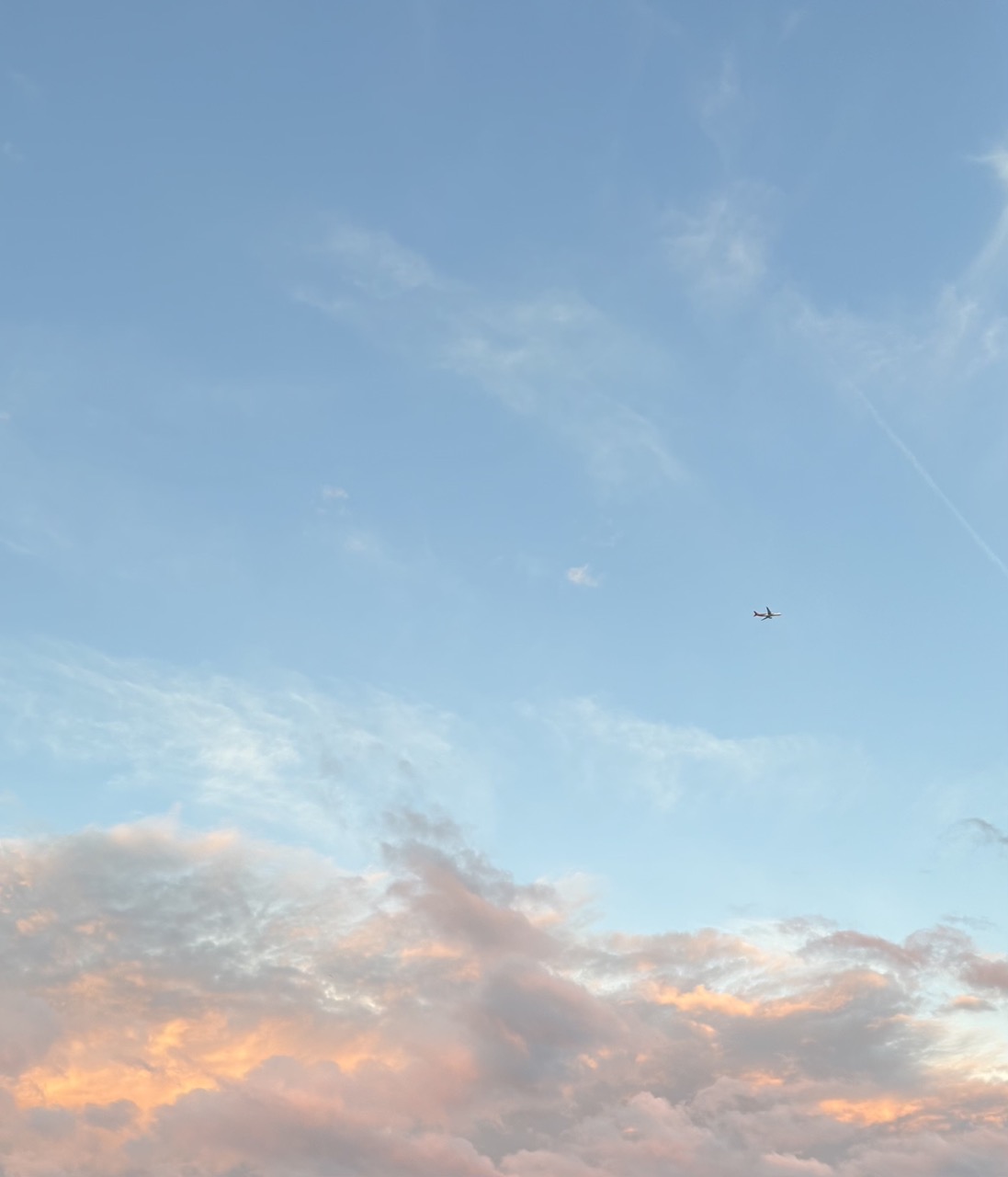 A plane 
above afternoon clouds